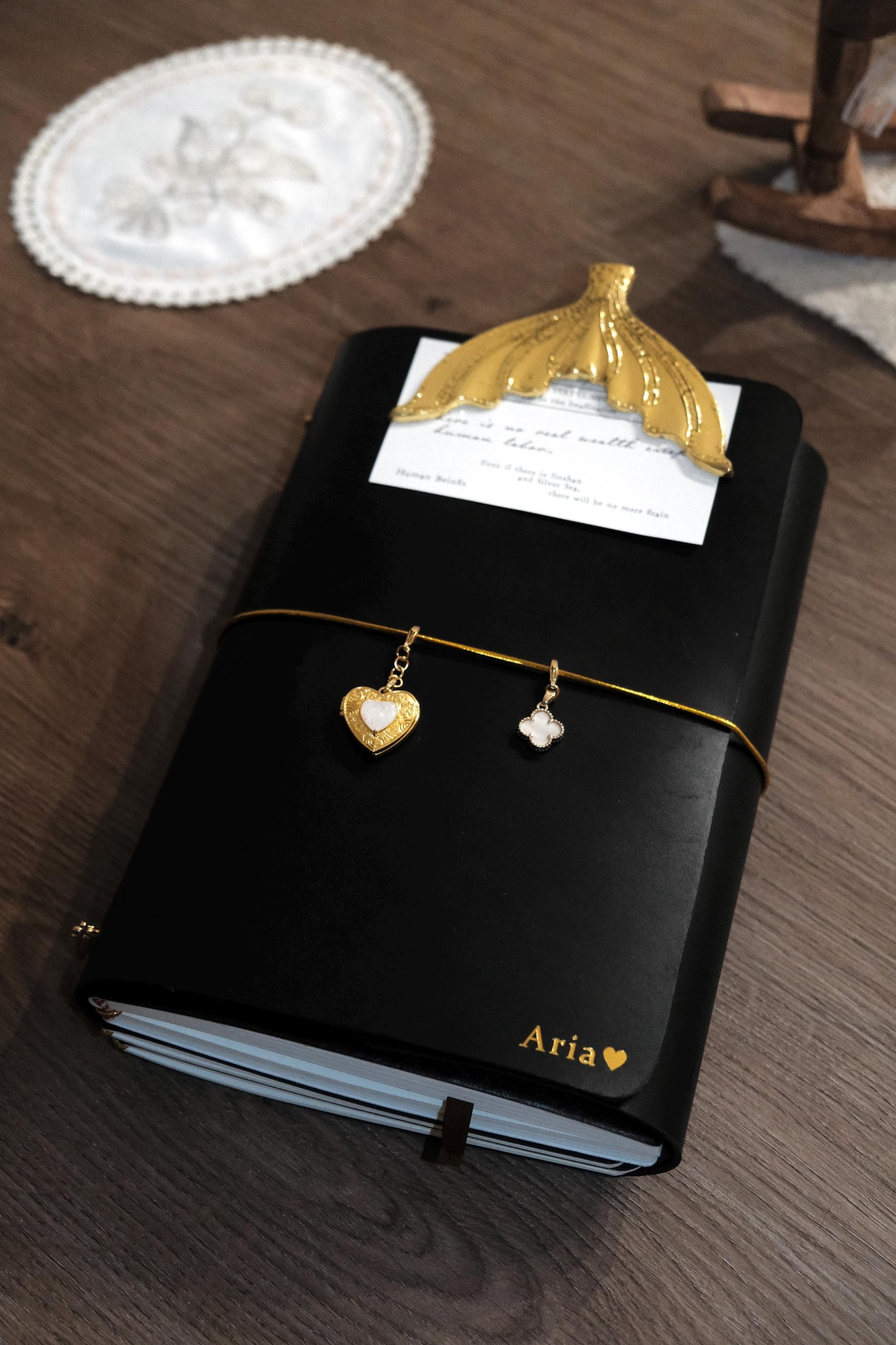 Handmade black trifold leather journal with personalized gold embossing and decorative charms